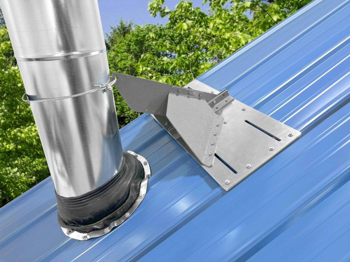 Standing seam VentSaver mounting plate and snow-diversion fin installed beside a metal vent pipe